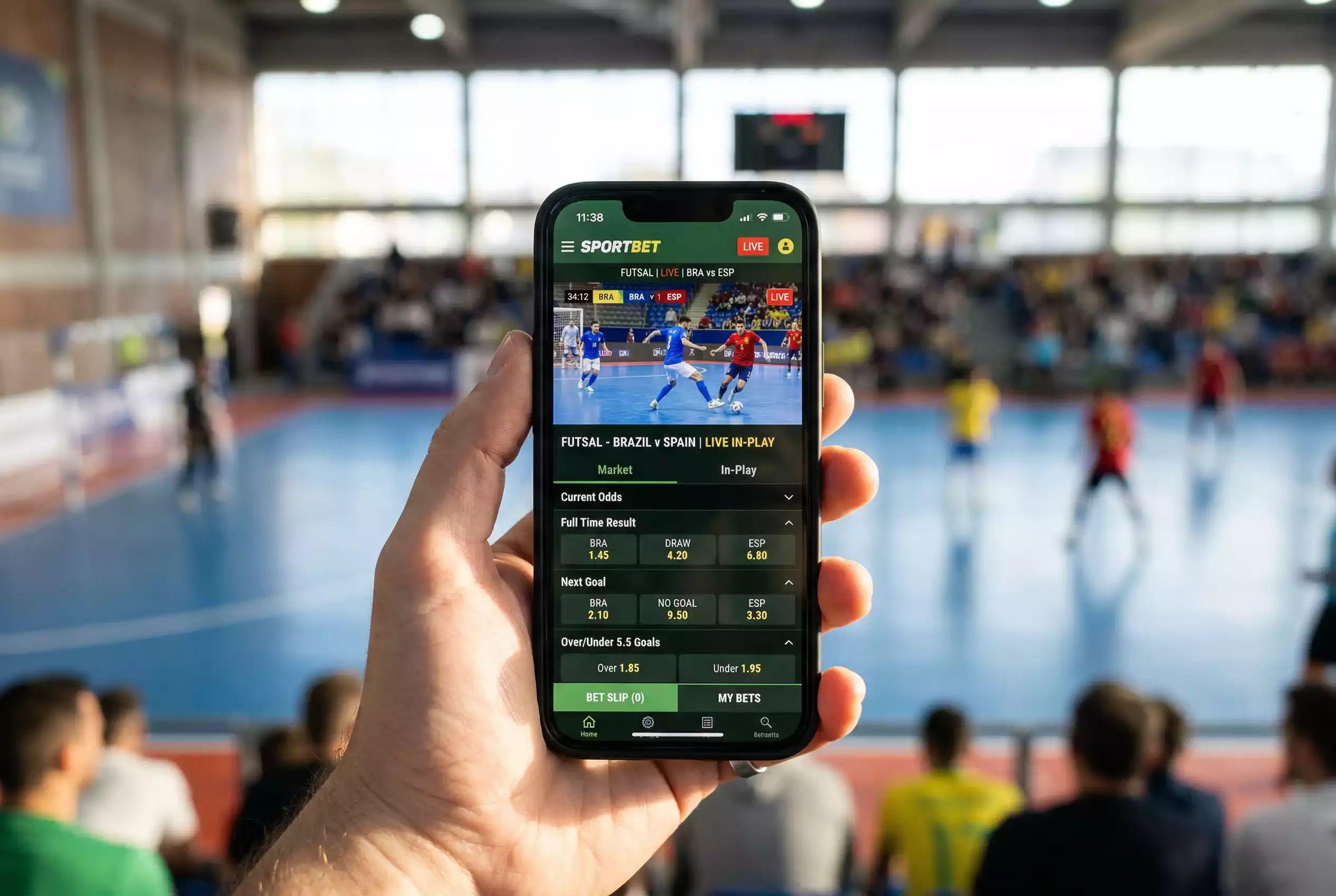 Mão a segurar telemóvel com aplicação de apostas e jogo de futsal no ecrã