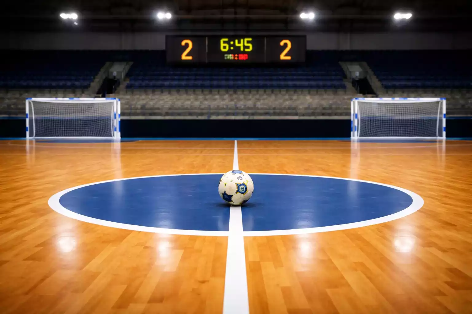 Bola de futsal junto a duas balizas com marcadores de golos para ambas equipas